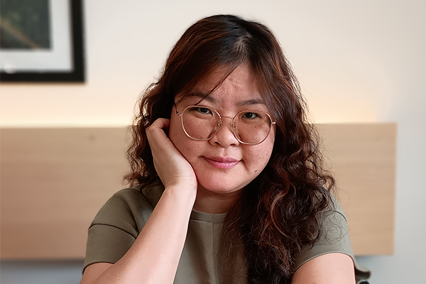 Kim Hoang Nguyen sitting at a table with water glasses and a cappuccino