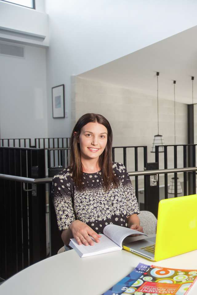 CQU student studying on campus with yellow laptop and smiling