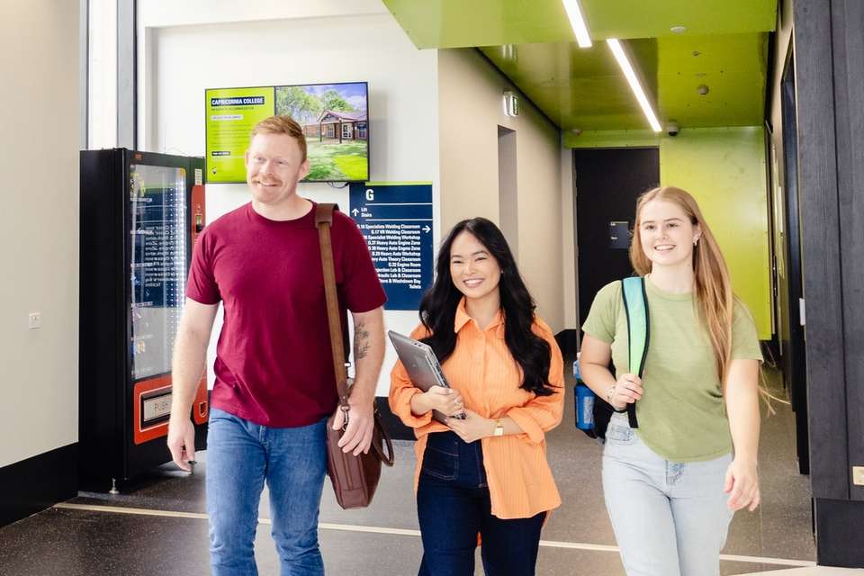 Three CQU students walk together through an on-campus building.