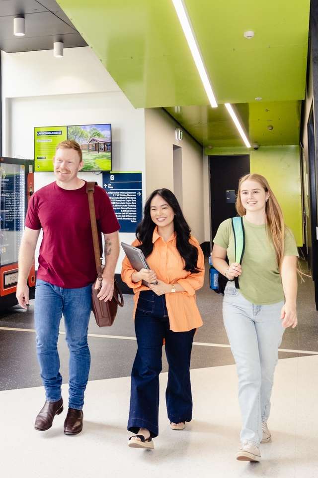 Three CQU students walk together through an on-campus building.