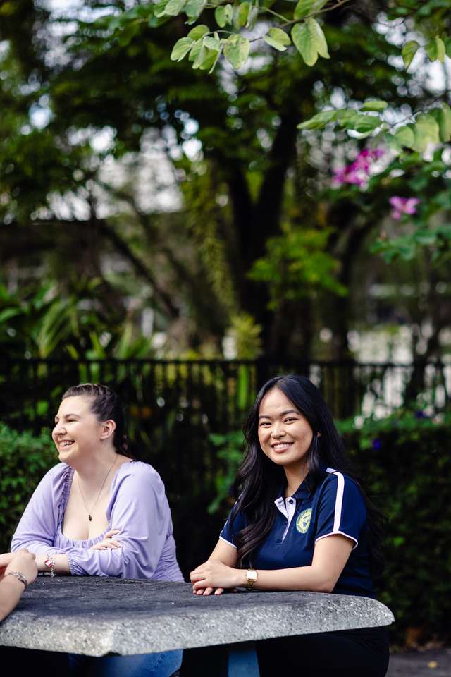 Student representative council member sitting at a table with peers, smiling at camera.