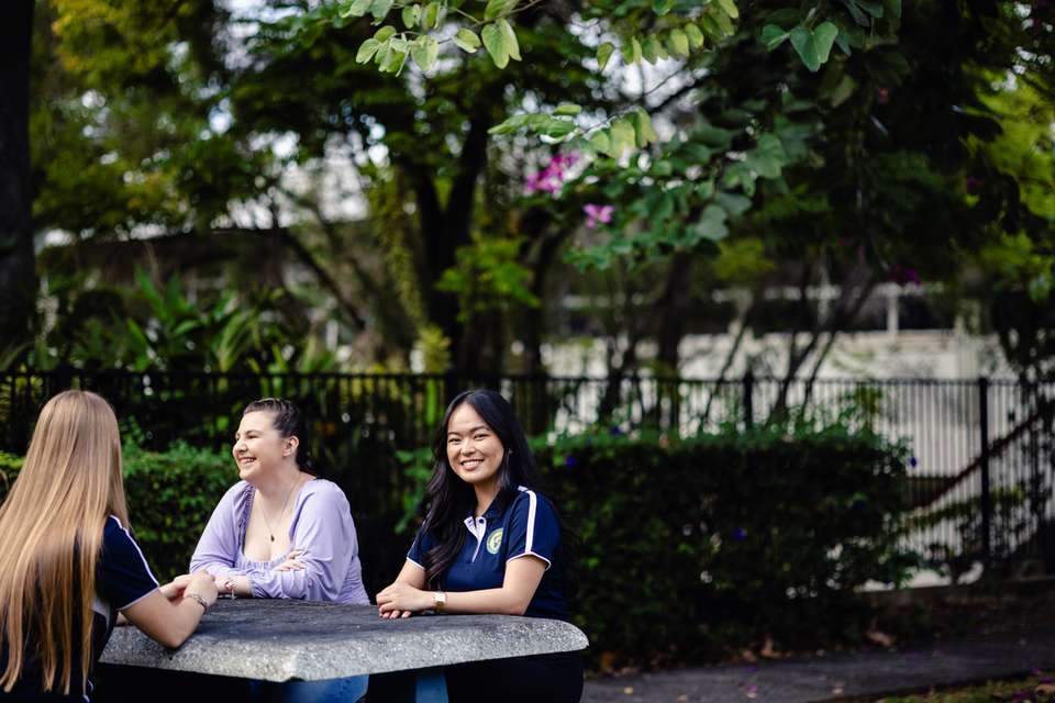 Student representative council member sitting at a table with peers, smiling at camera.