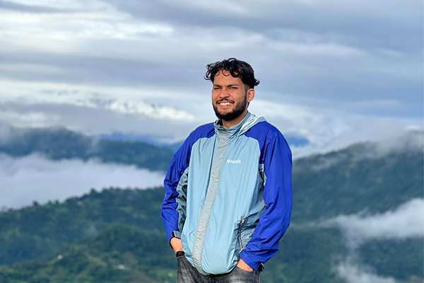 Asbin Kunwar standing with a cloudy mountain landscape in the background