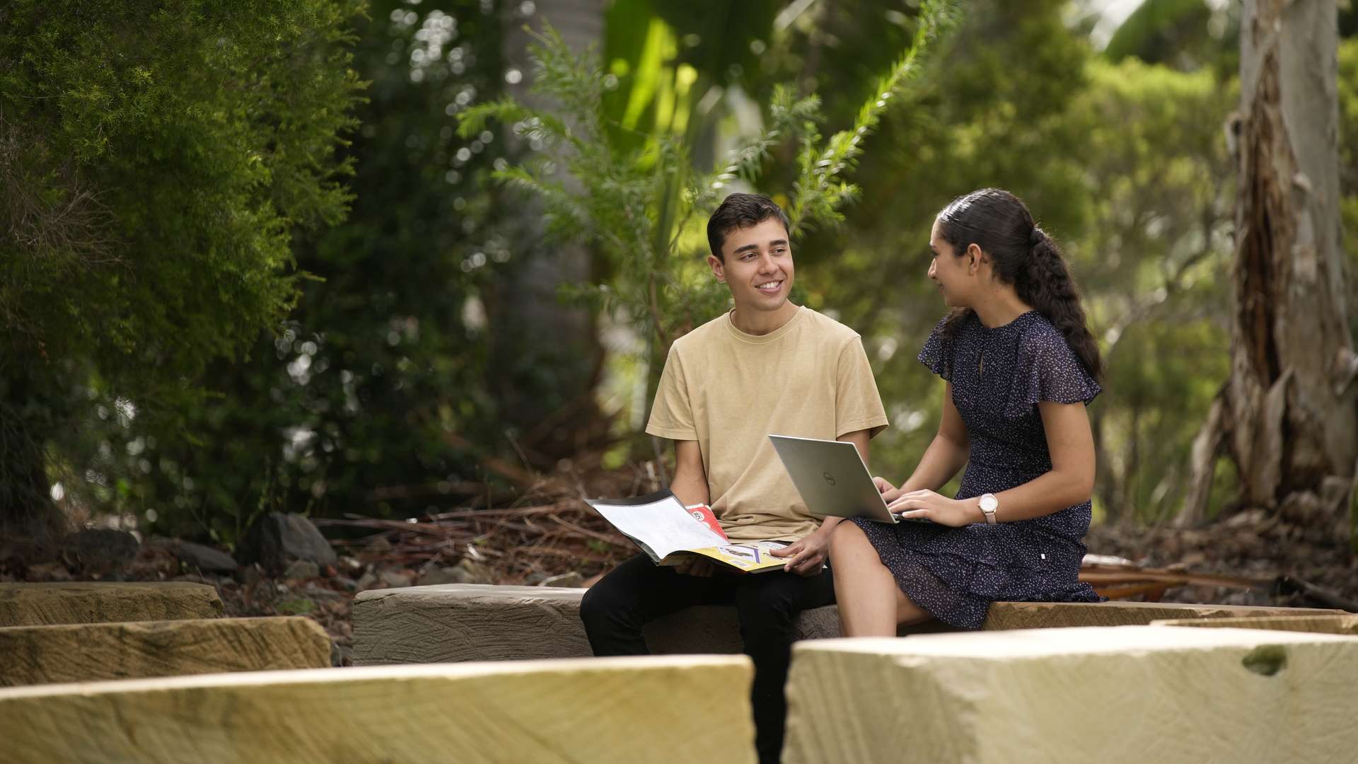 Two students studying and talking amongst each other whilst sitting in a yarning circle.