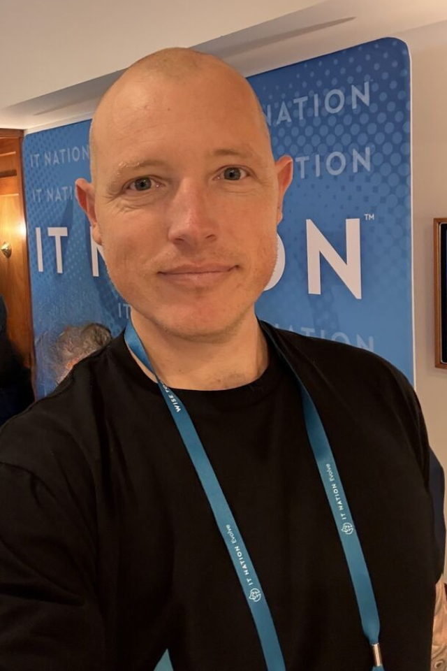 Alumnus Geoff Augutis wearing a black top and lanyard