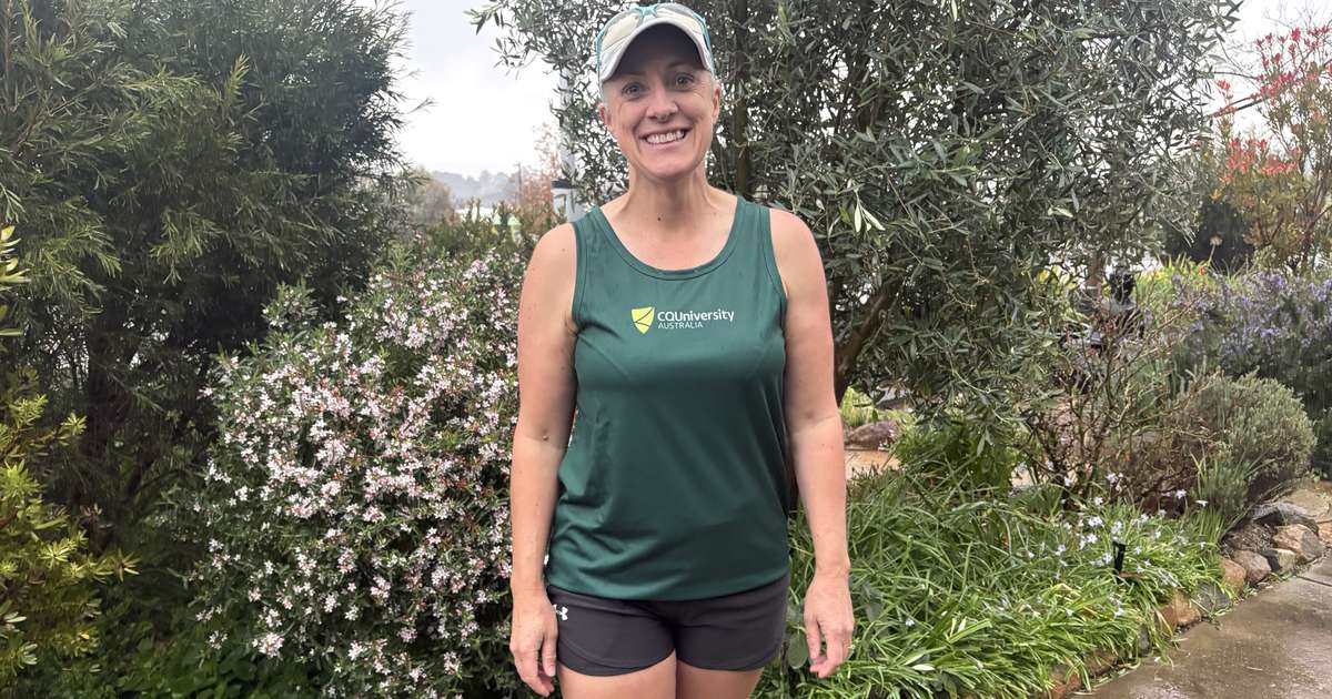 Prof Rachel Bacon stands outdoors wearing a green CQU running singlet and smiling.