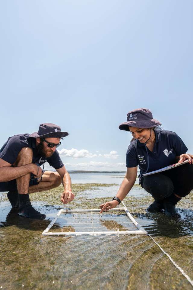 two students working together to measure water with a white rope