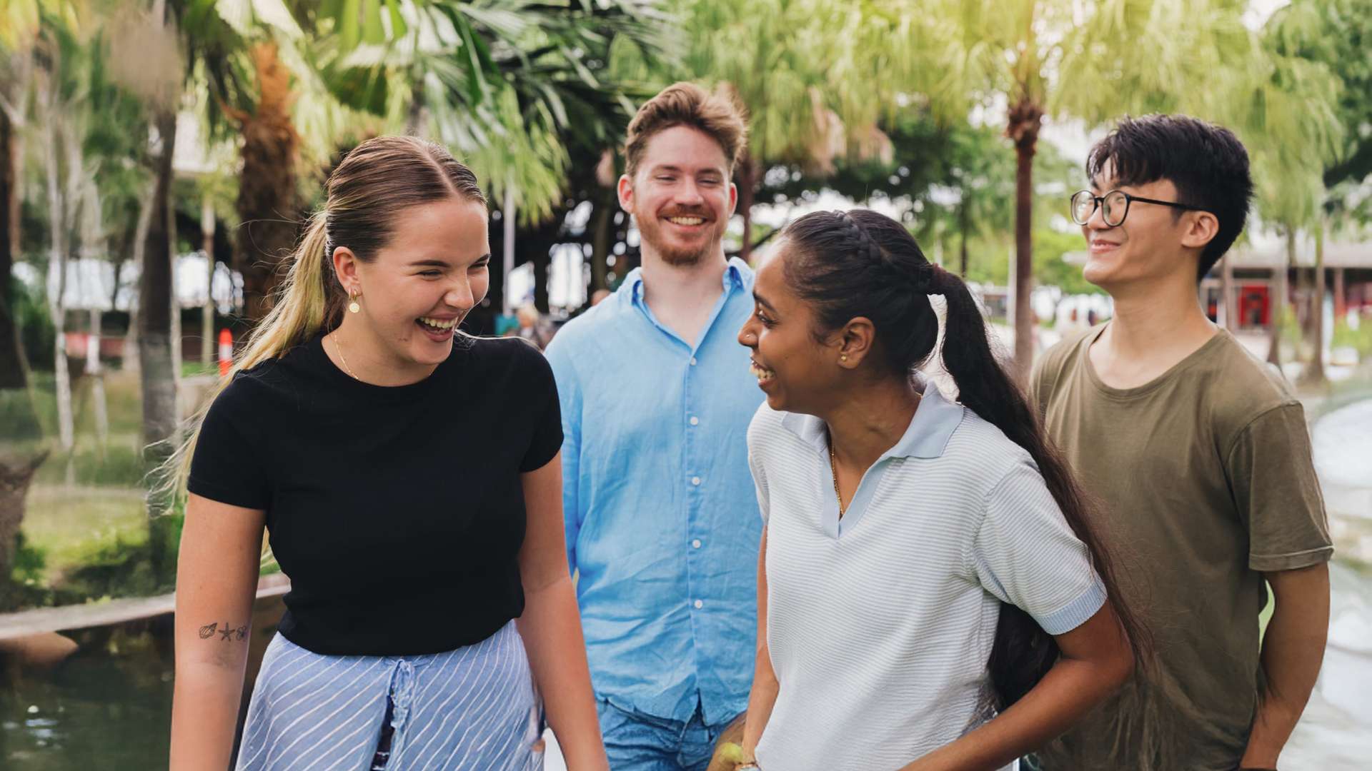 Four students smiling and laughing on Cairns campus esplanade